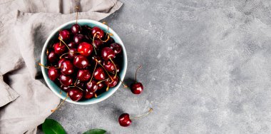 Açık gri arkaplan manzaralı olgun bir kiraz, masanın üstünde yazlık böğürtlen, metin için fotokopi alanı olan internet afişi.