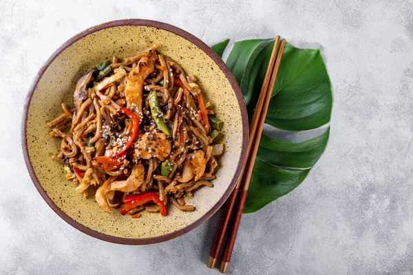 Asya karabuğday lapası sebzeli soba eriştesi, mantar ve açık gri arka plan manzaralı tavuk.