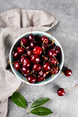 Açık gri arka plan manzaralı olgun bir kiraz, masanın üzerinde dikey yaz meyveleri.