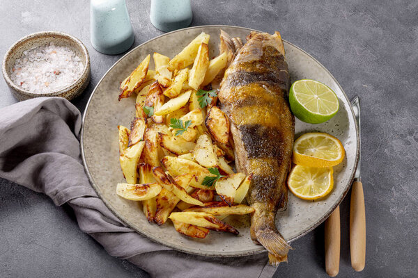 Baked sea bass or lingcod fish with potatoes on a plate on the table