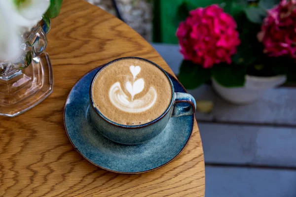 Eine Tasse Cappuccino-Kaffee und Blumen auf einem Tisch in einem Café — Stockfoto