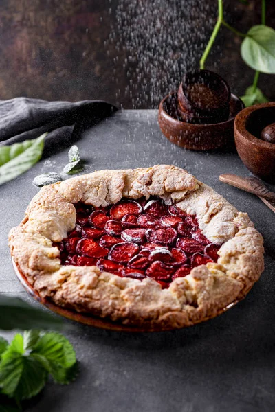 Цукрову пудру наливають на домашній пиріг з полуницею на столі, літню випічку з ягодами, вертикальне фото з місцем для тексту — стокове фото