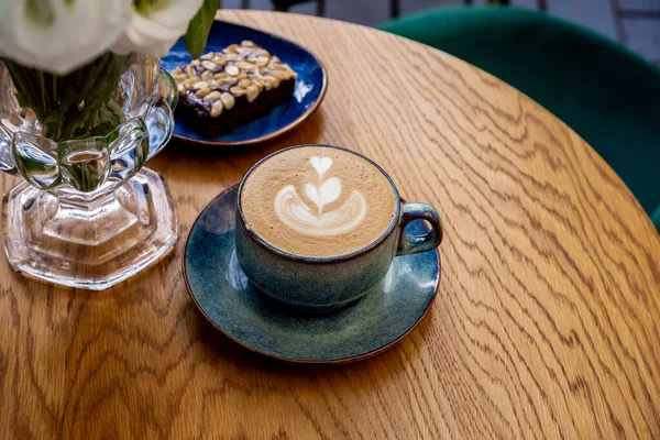 Eine Tasse Cappuccino-Kaffee und Blumen auf einem Tisch in einem Café — Stockfoto