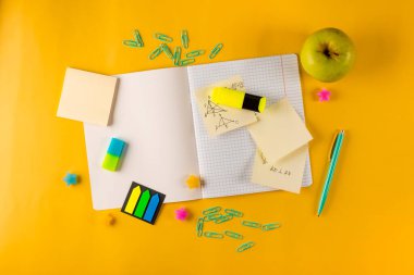  Sarı arka planda defter ve kırtasiye malzemesi, okula dönüş konsepti.
