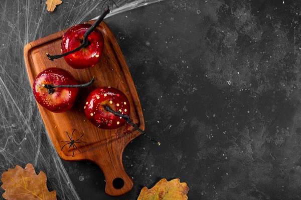 Manzanas rojas en caramelo con una decoración de Halloween festiva, un regalo original para una mesa de Halloween festiva decorada con arañas y telarañas, espacio de copia de vista superior para el texto — Foto de Stock