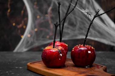  Cadılar Bayramı dekorlu kırmızı elmalar, örümcekler ve örümcek ağlarıyla süslenmiş bayram sofrası için orjinal bir ziyafet, metin için kopya alanı.