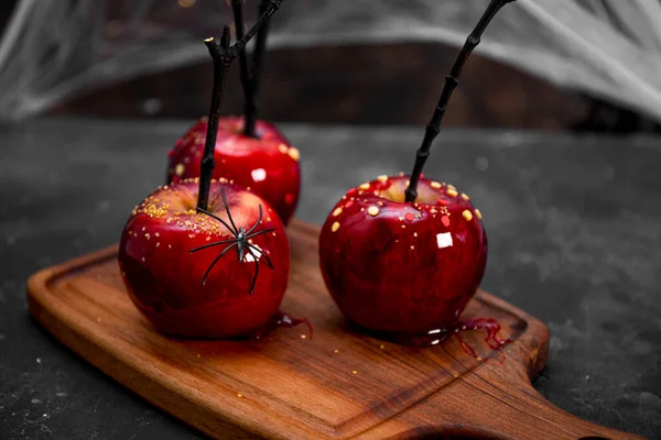 할로윈 장식 이 있는 카라멜에 있는 붉은 사과, 거미와 거미줄로 장식된 할로윈 테이블을 위한 원초적 인 요리 — 스톡 사진