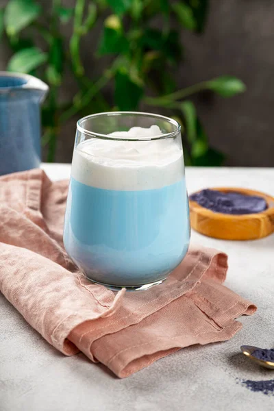 A glass of blue matcha latte, new trendy superfood healthy food, vertical photo
