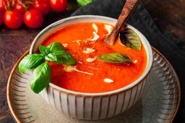  Masanın üzerinde kremalı ve fesleğenli geleneksel İspanya domates çorbası. Gri bir kasede domates ve fesleğen çorbası.