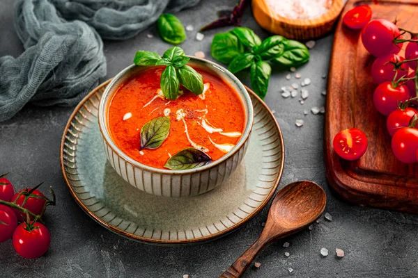  Masada krema ve fesleğenli geleneksel İspanya domates çorbası. Gri bir kasede domates ve fesleğen çorbası.