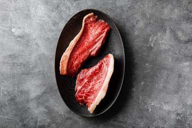  Siyah tabakta çiğ mermer biftek ve koyu gri arka plan, üst manzara. Mutfak masasında çiğ et. Yüksek kalite fotoğraf