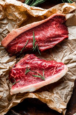  Çiğ mermer biftekler ve eski ahşap arka plan, üst manzara, dikey fotoğraf için baharatlar. Mutfak masasında çiğ et var.