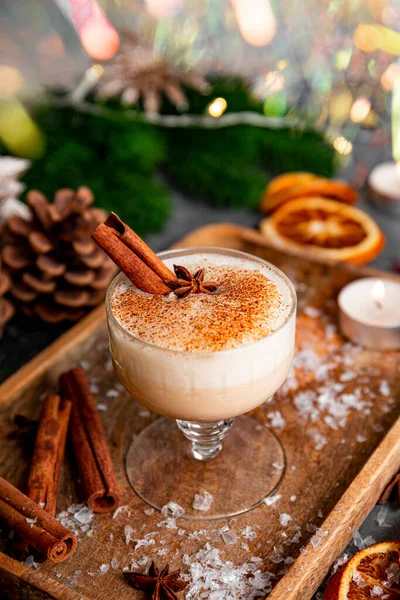 Un vaso de bebida tradicional de Navidad ponche de huevo en una mesa festiva, foto vertical. Bebida picante hecha de huevo y leche con canela, cardamomo. —  Fotos de Stock