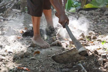 İşçilerin ayakları ve elleri çapa saplarını tutarken tozlu bahçedeki taşları ve toprağı temizlerken