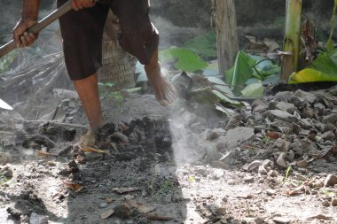 İşçi işçiler tozlu topraklarda fotokopi alanı ile çalışırken kayalık zemini düzleştiriyor.