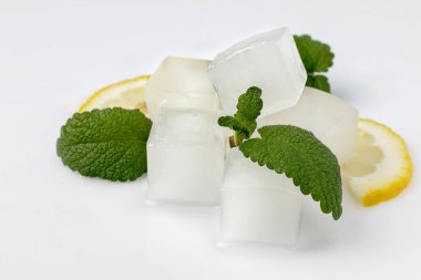 Buz küpleri, limon dilimleri ve beyaz arka planda izole edilmiş nane yaprakları..