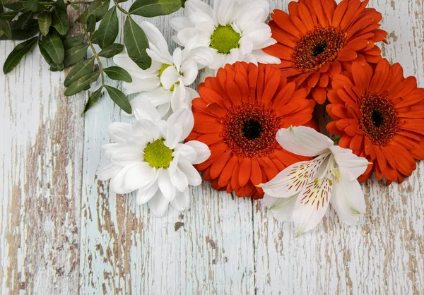 Bir buket kırmızı gerbera, beyaz zambaklar ve papatyalar, ahşap arka planda izole edilmiş..