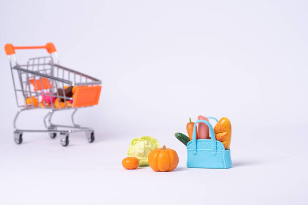 маленькая тележка для покупок игрушек на белом фоне, пространство для копирования, концепция покупок. Реалистичная тележка супермаркета, пустая корзина для покупок для покупателя.
