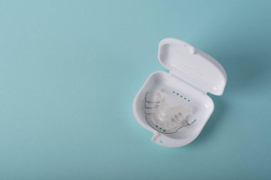 Diş tellerini ya da mavi arkaplandaki görünmez diş tellerini inceleyin. Ortodonti ya da parantez içinde. Yakın plan. Mavi arkaplanda parantezleri veya görünmez saydam hizalayıcıyı görüntüle