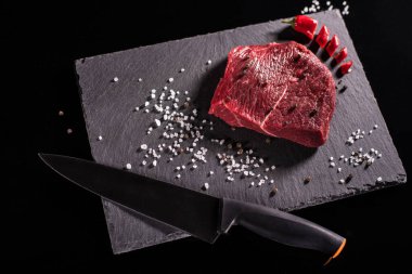 Izgara biftek ya da tuzlu dana biftek ve siyah taş tabakta. Et bıçağı. Üst görünüm.