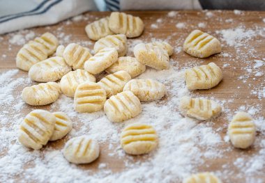 Ahşap pasta tahtasında un bulunan ev yapımı gnocchi. El yapımı gnocchi di patata, geleneksel İtalyan patatesli erişte..