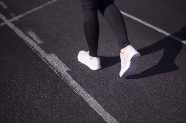 Sağlıklı yaşam tarzı bir spordur. Genç bayan koşucu şehre koşmadan önce ısınıyor. Koşu bandında koşan atlet ayakları ayakkabıya yakın plan..