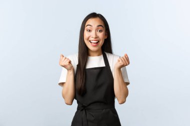 Coffee shop, small business and startup concept. Cheerful asian girl winning, best employee month, fist pump and rejoicing. Happy barista jumping enthusiastic, winning competition clipart