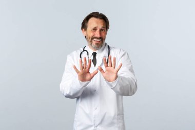 Covid-19, koronavirüs salgını, sağlık çalışanları ve pandemik konsept. Memnuniyetsiz ve rahatsız edici bir doktor korkunç bir şeyi reddediyor, reddederek ya da inkar ederek el sıkışıyor, telaşlı görünüyor.