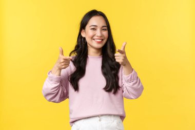 Yaşam tarzı, duygular ve reklam konsepti. Havalı havalı Asyalı havalı hippi kız, kamerayı gösterip gülümsüyor, davetlileri etkinliğe davet ediyor, tebrik ediyor ya da övüyor.