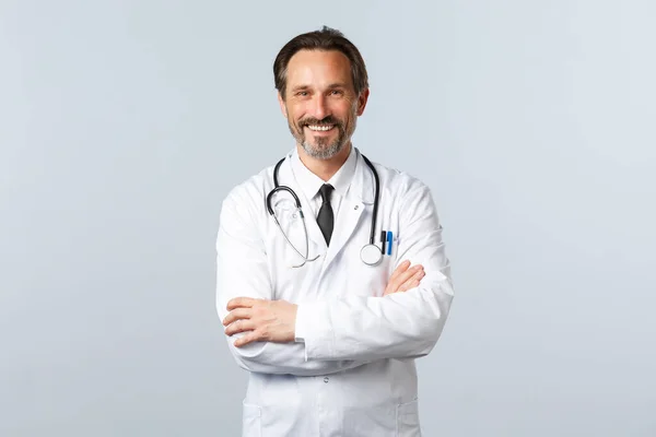 Covid-19, ξέσπασμα του ιού της στέψης, επαγγελματίες υγείας και πανδημία. Ενθουσιαστικός χαμογελαστός γιατρός, γιατρός με λευκό παλτό που δείχνει ενθουσιώδης, σταυρωτά χέρια στο στήθος, ακούγοντας τον ασθενή — Φωτογραφία Αρχείου