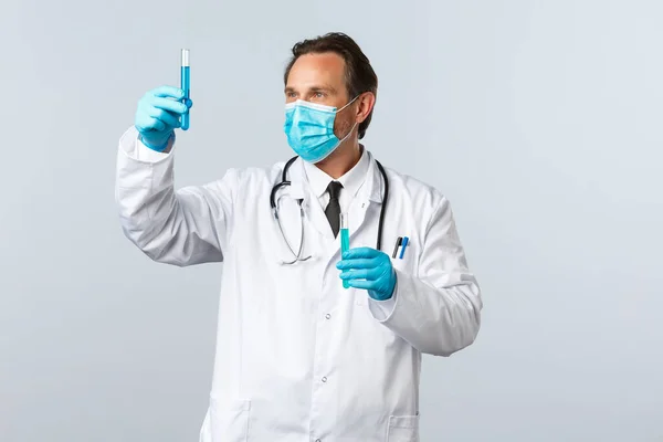Covid-19: 바이러스 예방, 의료 종사자 및 예방 개념. 의료 마스크와 코로나 바이러스 백신으로 시험관을 보고 있는 진지 한 의료 검 사실 의사 — 스톡 사진