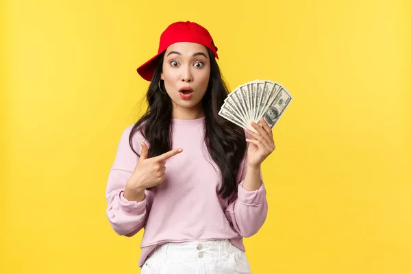 People emotions, lifestyle leisure and beauty concept. Surprised and amazed, overwhelmed cute asian girl with lots of cash, pointing at money and drop jaw, win lottery, got bonus for good work — Stock Photo, Image