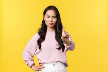 İnsan duyguları, yaşam tarzı ve moda kavramı. O kadar çabuk değil. Ciddi görünümlü, kendine güvenen Asyalı bir kız bir şeyi reddediyor, onaylamamak, reddetmek ya da yasaklamak için parmağını sallıyor.