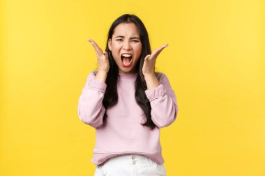 Yaşam tarzı, duygular ve reklam konsepti. Kızgın üzgün Asyalı kadın nefret dolu ve öfkeli bağırıyor, kötü haberler karşısında bunalmış hissediyor, korkunç bir duruma tepki veriyor, deli gibi hissediyor.