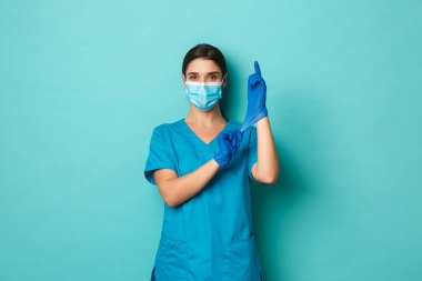 Covid-19, salgın hastalık ve ilaç konsepti. Kendine güvenen, tıbbi maske takan, eldiven takan ve kendinden emin görünen, hasta kontrolüne hazırlanan güzel bir kadın.