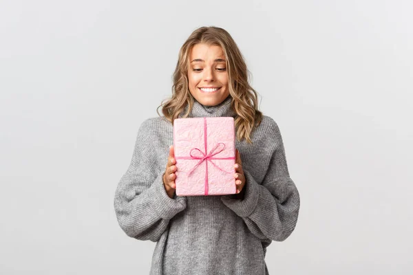 Stúdió lövés gyönyörű álmodozó lány megkapja a születésnapi ajándék, néz boldog jelen és mosolygós, érzés hálás, áll a fehér háttér — Stock Fotó