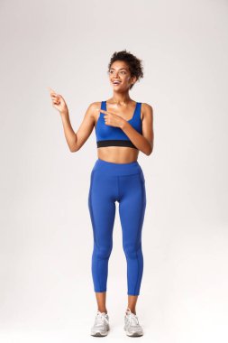 Afro-Amerikalı bir sporcunun gülümsemesi, bir şeye mutlu görünmesi, sol elini göstermesi, beyaz arka planda durması...