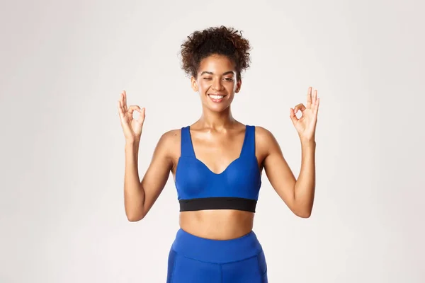 Waist-up van gezonde en sterke Afrikaans-Amerikaanse vrouwelijke atleet, knipogen en glimlachen, met goede tekenen, staande over witte achtergrond — Stockfoto