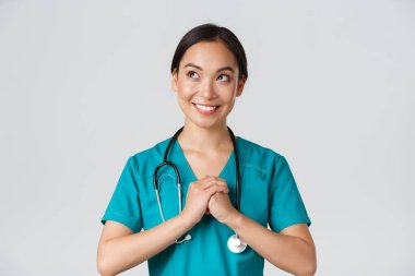 Sağlık çalışanları, virüsü önleme, karantina kampanyası konsepti. Kararlı ve kendinden emin, önlüklü Asyalı kadın doktor ellerini kenetleyip, hazırlanıyor, sol üst köşeye bakıyor.