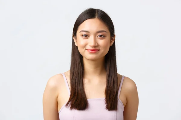 Belleza, moda y gente concepto de emociones. Primer plano retrato de hermosa chica asiática en vestido sonriendo feliz cámara, mirando lindo y de pie sobre fondo blanco —  Fotos de Stock