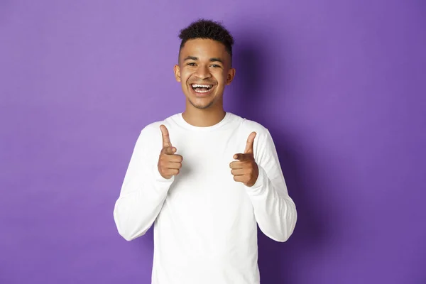 一个快乐的非洲裔美国年轻人的形象，用手指指着相机笑着，称赞好的选择，祝贺某事，站在紫色的背景上 — 图库照片