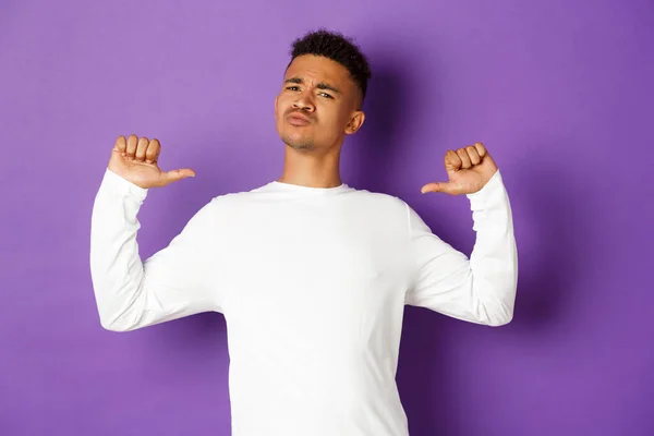 Imagem de homem afro-americano confiante e bonito, apontando para si mesmo com rosto orgulhoso, em pé auto-confiante sobre fundo roxo — Fotografia de Stock