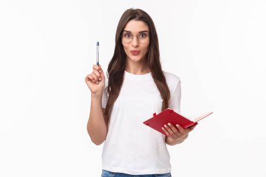 Yaratıcı hevesli genç bayanın harika bir fikri var, not defterine unutmamak için, kalemini Eureka işareti ile yükseltmek, heyecanla gülümsemek, hazırlık planı veya günlük program, beyaz arka plan