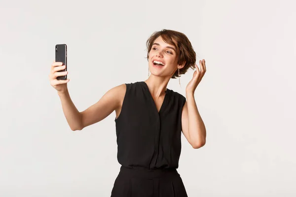 Stylová mladá žena se selfie na party, stojící bílé pozadí — Stock fotografie