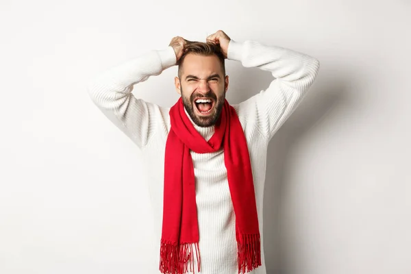 Weihnachtsurlaub und Neujahrskonzept. Frustrierter und wütender Mann reißt sich die Haare vom Kopf und schreit verzweifelt vor weißem Hintergrund — Stockfoto