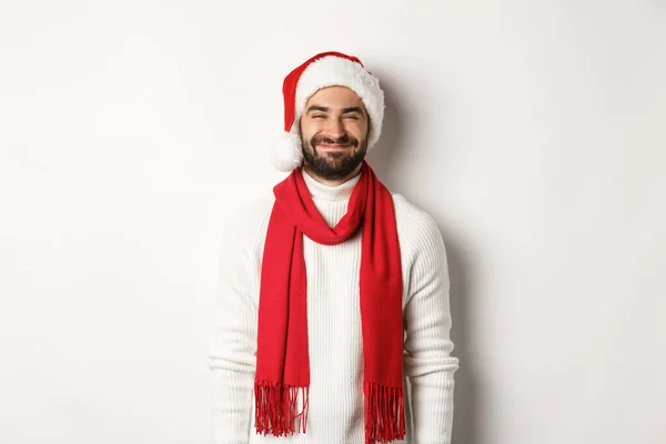 Weihnachtsferien. Bärtiger Mann mit Weihnachtsmütze und rotem Schal sieht glücklich aus, genießt Silvesterfeier, steht über weißem Hintergrund — Stockfoto