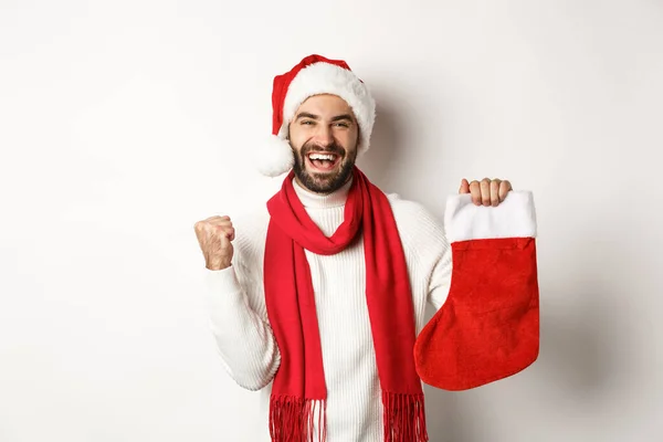 Férias de inverno e conceito de celebração. Homem feliz segurando meia de Natal e se alegrar, receber presente, de pé contra fundo branco — Fotografia de Stock