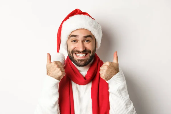 Festa de Ano Novo e conceito de férias de inverno. Close-up de homem feliz em chapéu de Papai Noel mostrando polegares para cima em aprovação, como e concordar, de pé sobre fundo branco — Fotografia de Stock