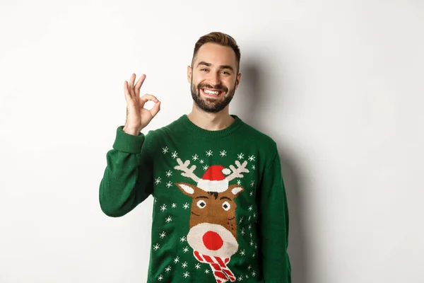 Zimní prázdniny a Vánoce. Šťastný vousatý muž ukazující dobrý znamení a usmívající se, schvalující nebo souhlasící, chválí něco dobrého, stojí nad bílým pozadím — Stock fotografie