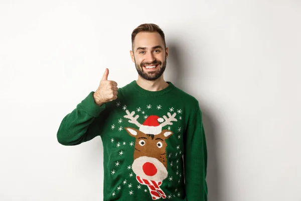 Zimní prázdniny a Vánoce. Šťastný vousatý muž ukazující palec na souhlas, jako něco, chvála dobré práci, stojící nad bílým pozadím — Stock fotografie